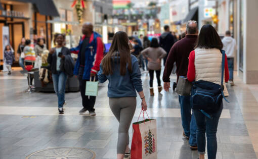 Inside a busy shopping centre with consumers walking by holding shopping bags